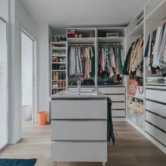 Un vestidor moderno con ducha, lavabo y amplios armarios para organizar ropa y zapatos.
