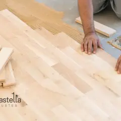 Man installing a light-colored suelo laminado, placing planks on adhesive.