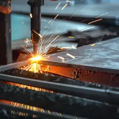 Chispa de corte de acero. Una máquina industrial realiza un corte de acero, lanzando chispas brillantes y creando un espectáculo de luz y calor.