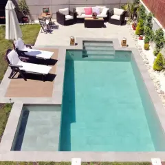 Un jardín listo para construir piscina, con tumbonas, zona de estar y barbacoa.