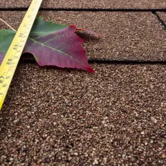 Medición de tejas en un metro cuadrado. Una hoja de otoño y cinta métrica sobre un tejado.