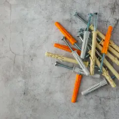 Montón de tacos de pared de varios colores (naranja, beige, gris) con tornillos. Listos para fijar cualquier cosa a la pared.
