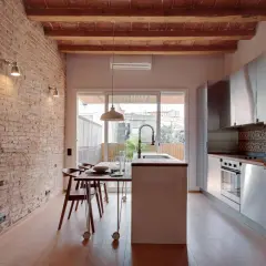 Cocina moderna con pared de ladrillo visto y pintura efecto envejecido. Vigas de madera en el techo y suelo de parqué.