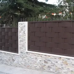 Muro de piedra con paneles de valla de metal marrón oscuro, un ejemplo de tipos de vallas para chalet.
