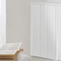 Un radiador de mica blanco, moderno y eficiente, calienta la estancia. A su lado, un libro abierto invita a la lectura.
