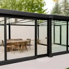 Modernos tipos de cerramientos de cristal con mesa y sillas en el interior, creando un espacio elegante y luminoso.