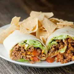 Un taco quimico como funciona: carne molida, lechuga, tomate y queso envueltos en tortilla, servido con totopos.