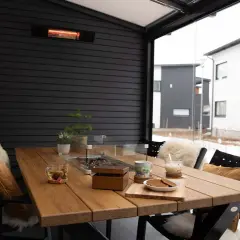 Mesa de madera en terraza cerrada con calefactor, ideal para disfrutar del exterior incluso con nieve.