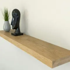 Estantería flotante de madera, ideal para poner baldas en pared sin escuadras. Decorada con un busto negro y una planta.