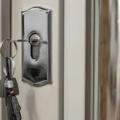 Un juego de llaves cuelga de una cerradura de puerta plateada, mostrando varios tipos de cerraduras.