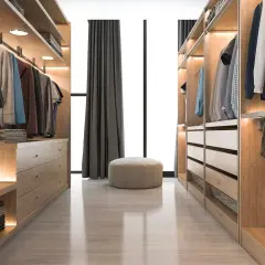 Un vestidor cerrado de madera clara, con ropa colgada y cajones organizados. Un puf beige y cortinas oscuras completan la escena.