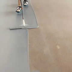 Persona pintando el suelo con una llana, aplicando una capa gris sobre una superficie texturizada.
