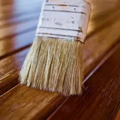 Brocha aplica barniz a listones de madera, dándoles un acabado brillante. El proceso de blanquear madera puede ser el primer paso para un nuevo look.