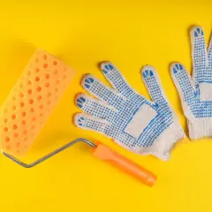 Rodillo de esponja naranja y guantes de trabajo azules, listos para diferentes tipos de rodillos para pintar.
