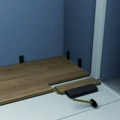 Instalación de suelo laminado con tacos para rodapiés. Se aprecian varios tipos de rodapiés y herramientas para su colocación.