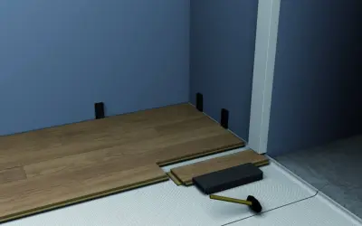 Instalación de suelo laminado con tacos para rodapiés. Se aprecian varios tipos de rodapiés y herramientas para su colocación.