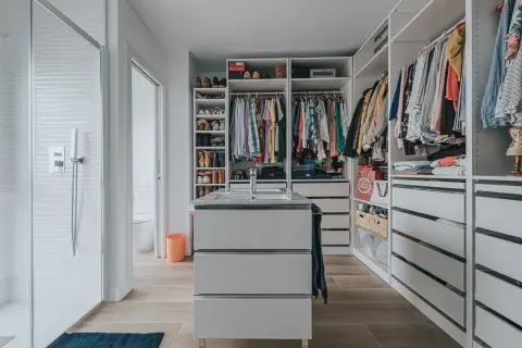 Un vestidor moderno con ducha, lavabo y amplios armarios para organizar ropa y zapatos.