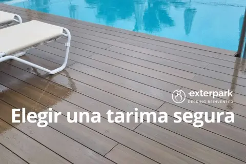 Terrazas de madera junto a una piscina, con tumbonas. El suelo de madera está mojado, reflejando la luz.