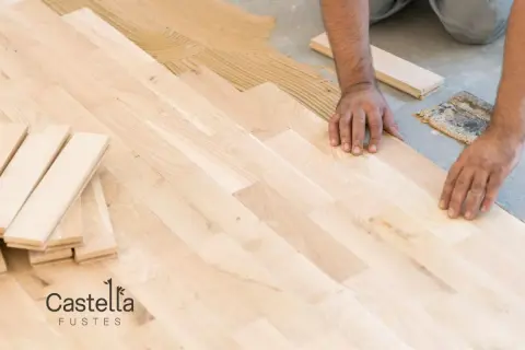 Man installing a light-colored suelo laminado, placing planks on adhesive.