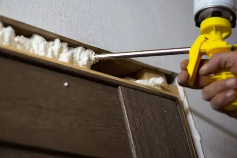 Aplicando espuma de poliuretano para sellar huecos. Si necesitas saber como quitar la espuma de poliuretano, este es el primer paso.