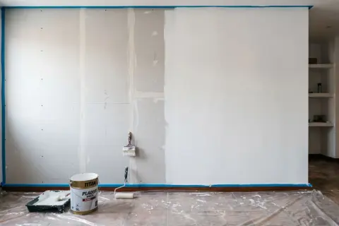 Pintar pladur es un proceso que requiere paciencia. Aquí, una pared a medio pintar, con rodillo y brocha listos para continuar.