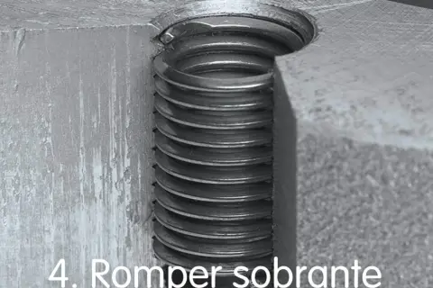 Detalle de un tornillo pasado de rosca, con las espiras metálicas visibles y dañadas.