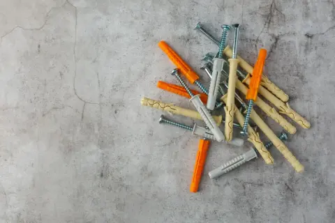 Montón de tacos de pared de varios colores (naranja, beige, gris) con tornillos. Listos para fijar cualquier cosa a la pared.