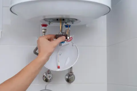 Mano ajustando componente de calentador de agua, parte de un tutorial sobre como limpiar un termo por dentro.