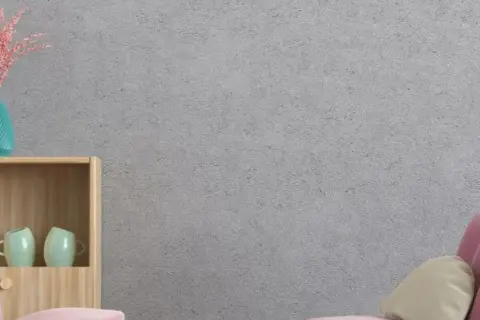 Estantería de madera con tazas, jarrón y un cojín sobre un sofá rosa. La pared tiene un acabado de gotelé, ideal para aplicar papel pintado sobre gotele.