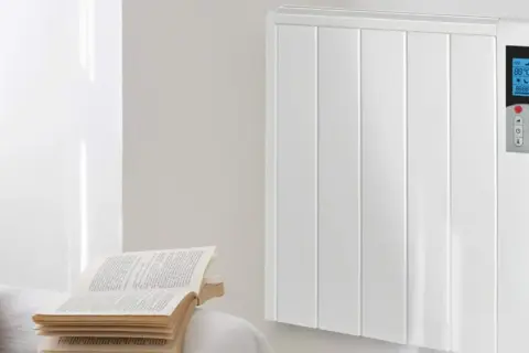 Un radiador de mica blanco, moderno y eficiente, calienta la estancia. A su lado, un libro abierto invita a la lectura.