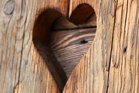 Corazón tallado en madera rústica, mostrando el encanto del envejecer madera.