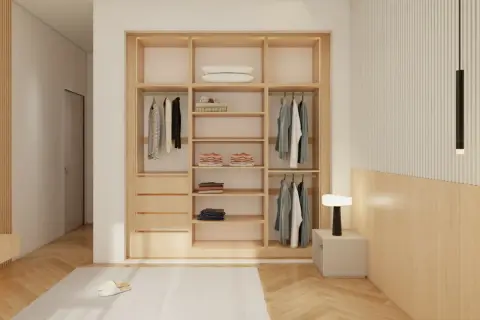 Armario empotrado de madera con puertas correderas, ropa colgada y doblada, y una lámpara de noche.