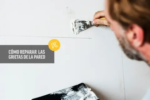 Hombre aplicando masilla para reparar grietas en la pared. Aprende cómo reparar grietas en la pared con esta guía visual.