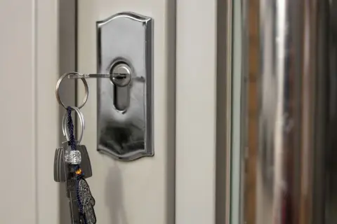 Un juego de llaves cuelga de una cerradura de puerta plateada, mostrando varios tipos de cerraduras.