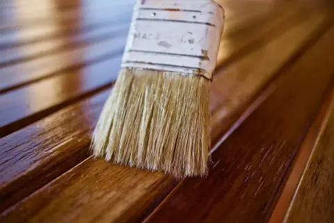 Brocha aplica barniz a listones de madera, dándoles un acabado brillante. El proceso de blanquear madera puede ser el primer paso para un nuevo look.