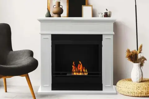 Chimenea blanca con fuego encendido. Si tu chimenea hace humo, aquí tienes consejos sobre como arreglar una chimenea que hace humo.