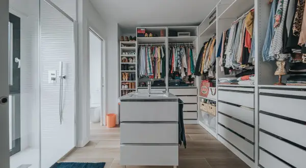 Un vestidor moderno con ducha, lavabo y amplios armarios para organizar ropa y zapatos.