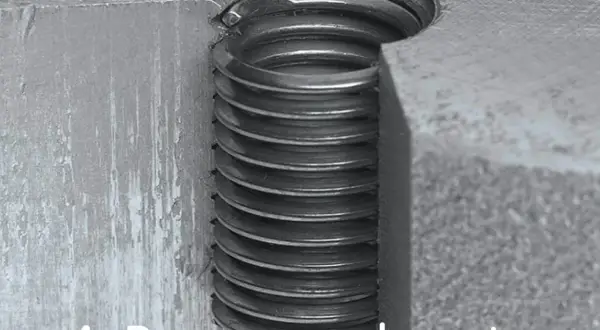 Detalle de un tornillo pasado de rosca, con las espiras metálicas visibles y dañadas.