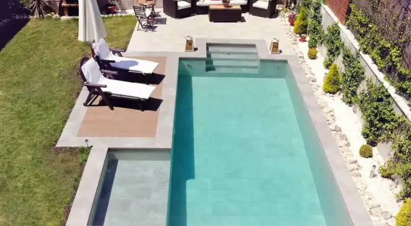 Un jardín listo para construir piscina, con tumbonas, zona de estar y barbacoa.
