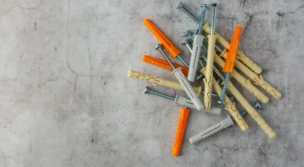 Montón de tacos de pared de varios colores (naranja, beige, gris) con tornillos. Listos para fijar cualquier cosa a la pared.