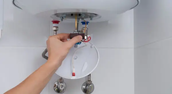Mano ajustando componente de calentador de agua, parte de un tutorial sobre como limpiar un termo por dentro.