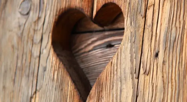 Corazón tallado en madera rústica, mostrando el encanto del envejecer madera.