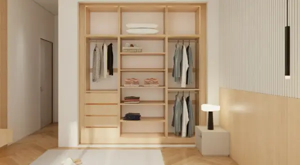 Armario empotrado de madera con puertas correderas, ropa colgada y doblada, y una lámpara de noche.