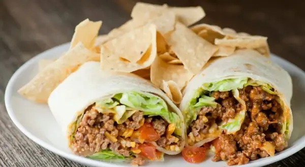 Un taco quimico como funciona: carne molida, lechuga, tomate y queso envueltos en tortilla, servido con totopos.