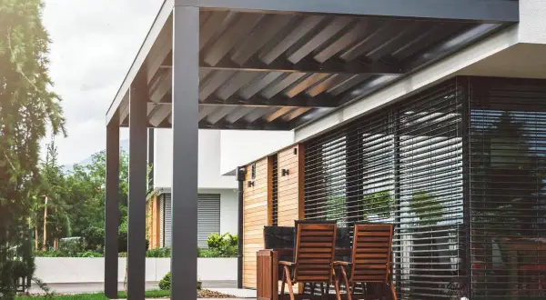 Elegante pérgola bioclimática con techo de lamas orientables. Los inconvenientes podrían ser el mantenimiento de las lamas y la posible acumulación de agua.