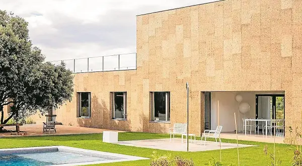 Fachada moderna con aislamiento acústico de corcho, piscina y jardín.