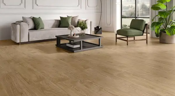 Elegante salón con sofá gris, sillón verde y un moderno revestimiento del suelo de madera clara que aporta calidez.