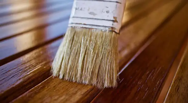 Brocha aplica barniz a listones de madera, dándoles un acabado brillante. El proceso de blanquear madera puede ser el primer paso para un nuevo look.