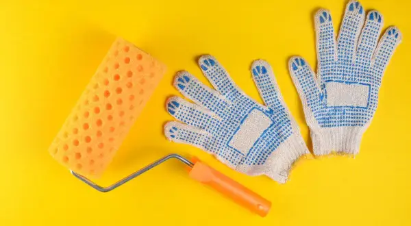 Rodillo de esponja naranja y guantes de trabajo azules, listos para diferentes tipos de rodillos para pintar.