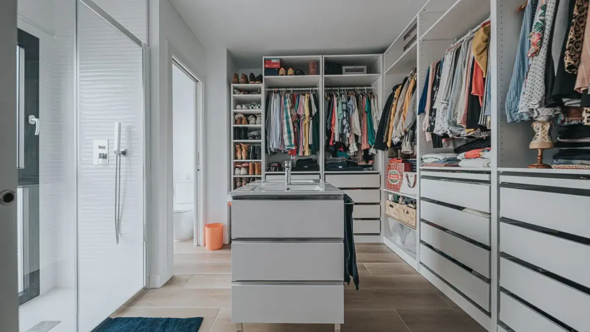 Un vestidor moderno con ducha, lavabo y amplios armarios para organizar ropa y zapatos.